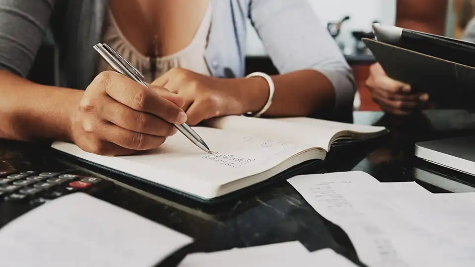 Close up of a woman writing in a note book.